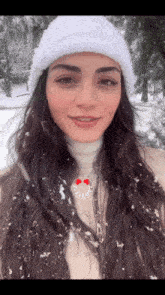 a woman wearing a white hat and a necklace with a heart on it stands in the snow