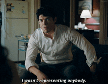 a man in a white shirt is sitting on a couch and saying i wasn 't representing anybody