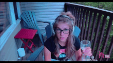 a girl wearing headphones and glasses is holding a glass of wine