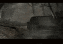 a car is driving down a road in a dark forest with a sign that says ' i am sorry ' on it