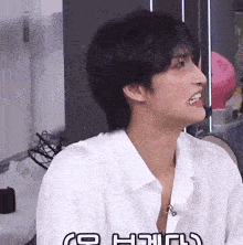 a man in a white shirt is smiling and looking to his left
