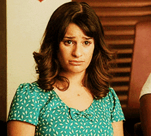 a woman wearing a blue shirt with leaves on it is making a sad face