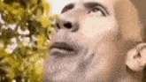 a close up of a man 's face looking up at the sky with a tree in the background .