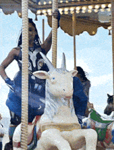 a woman is riding a merry go round with a unicorn statue