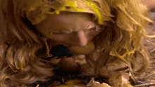 a woman with yellow paint on her head eating a banana