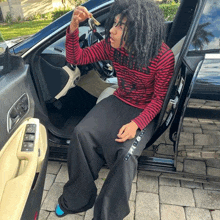 a young man with dreadlocks is sitting in the driver 's seat of a car holding a key .