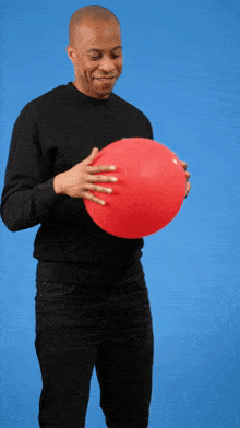 a man in a black shirt is holding a red balloon in his hands