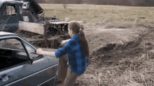 a woman is pushing a car in a field .