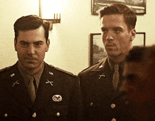 two men in u.s. army uniforms are standing next to each other in a room