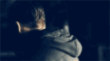 a man in a hoodie is standing in a dark room looking over his shoulder .