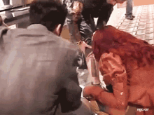 a group of people standing around a woman with red hair .