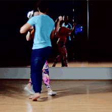 a man in a blue shirt is dancing with a woman in floral pants