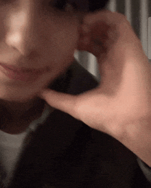 a close up of a person 's face with a hand covering their ear