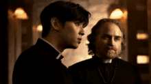 a priest and a young man are standing next to each other and talking .