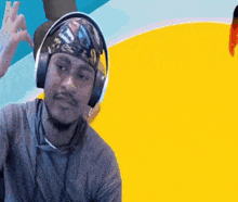 a man wearing headphones and a bandana is giving a peace sign .