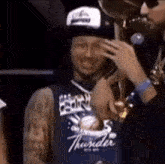 a man wearing a thunder jersey is holding a trophy .