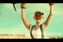 a woman wearing overalls and a hard hat is holding a hammer in her hands .