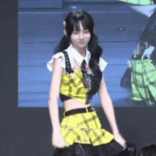 a girl in a yellow and black plaid dress is dancing