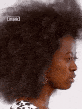 a woman with a big afro is wearing earrings and the word resay is on the bottom right