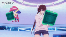 a girl in a pink sweater is holding a green box while another girl in a red hat is sitting behind her