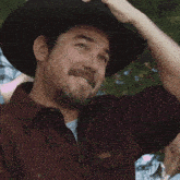 a man wearing a black cowboy hat is smiling