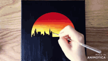 a person is painting a sunset with the words made in animotica below it
