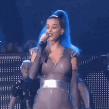 a woman with blue hair singing into a microphone on stage