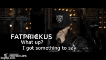 a man wearing a raiders hat is holding a microphone and talking into it .
