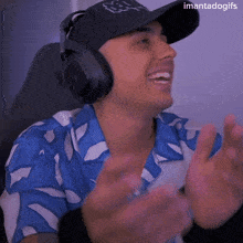 a man wearing headphones and a hat with the word fox on it is clapping his hands