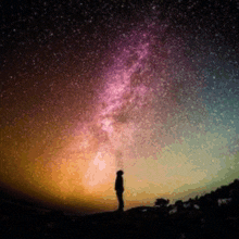 a silhouette of a person looking up at the milky way galaxy