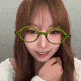 a woman wearing green glasses looks at the camera and smiles