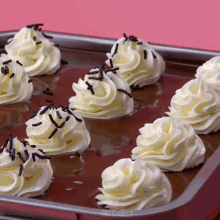 a pan filled with whipped cream and chocolate sprinkles on a pink background