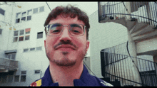 a man wearing glasses and a red bull jacket smiles