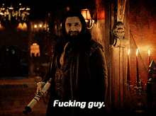 a man in a dark room with candles and a lamp says fucking guy