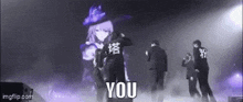 a group of people are dancing on a stage with a girl in a witch costume behind them .