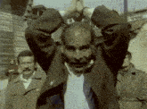 a man in a brown jacket is being held by two men
