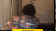 a man in a floral shirt is sitting on a couch in a living room .