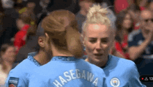 a group of female soccer players are hugging each other and one of them has the name hasegawa on her back