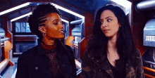 two women are standing next to each other in a room .