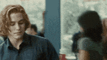 a man in a blue shirt looks at a woman in a green shirt