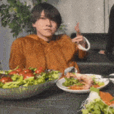 a man is sitting at a table with plates of food and a bowl of salad