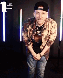 a man wearing a plaid shirt and a hat is standing in front of a sign that says beta awards