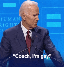 a man in a suit and tie stands at a podium and says coach i 'm gay