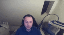 a man wearing headphones is sitting in front of a microphone in a bedroom .