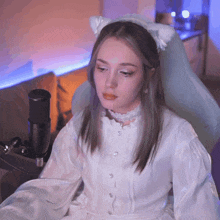 a woman in a white dress is sitting in a chair