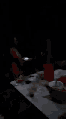 a group of people are sitting at a table in the dark .