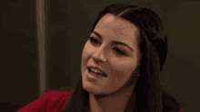 a woman is smiling and looking at the camera while wearing a red jacket .
