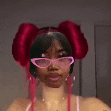 a woman wearing pink glasses and red balloons in her hair takes a selfie