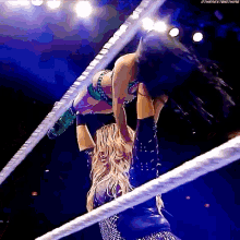 two women are wrestling in a ring and one of them is holding the other 's hand .