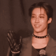 a woman wearing a choker and a jacket is smiling and talking into a microphone .